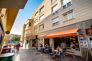 a group of people sitting at tables outside a building at Alquilaencanarias-Medano Tío Claudio beachfront in El Médano