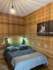 1 dormitorio con 1 cama en una pared de madera en L'apparté de G, Gîte 3 étoiles de montagne cosy, en Gérardmer