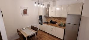 a kitchen with white cabinets and a table and a refrigerator at Apartament Calea Moldovei Residence - minibar si parcare GRATIS in Bistriţa