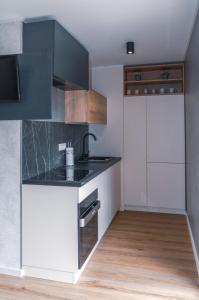 uma cozinha com armários brancos e um balcão preto em Mobilna hiška pod Lipo em Velenje