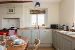 a kitchen with a wooden table and a kitchen with a sink at Luxury Farmhouse with Stunning Views and Hot Tub in Ebberston