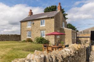 an old brick house with a table and chairs at Luxury Farmhouse with Stunning Views and Hot Tub in Ebberston
