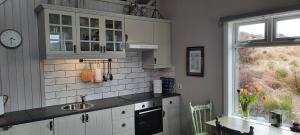 CarrickにあるHeather House on the Wild Atlantic Wayの白いキャビネット、シンク、窓付きのキッチン