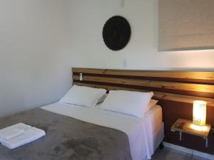 a bedroom with a large bed with a wooden headboard at Chalés e flats Recanto Primavera in Camburi