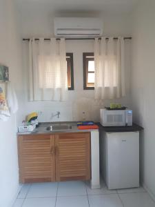a kitchen with a sink and a microwave at Chalés e flats Recanto Primavera in Camburi