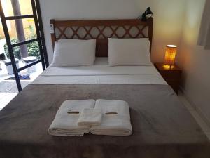 a bed with two white towels on it at Chalés e flats Recanto Primavera in Camburi