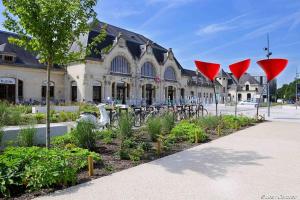 un bâtiment avec des parasols rouges en face d'un jardin dans l'établissement Le Petit Drouais T3 en plein Cœur De Ville !, à Dreux