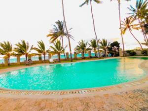 une grande piscine avec des palmiers et l'océan dans l'établissement SWEET BREEZE HOMES, à Mombasa