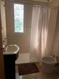 a bathroom with a white shower curtain and a sink at Departamento moderno con balcon in Olavarría