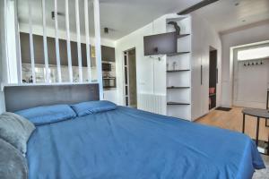 a bedroom with a blue bed and a kitchen at Le CoCoN de MaiNteNon in Maintenon