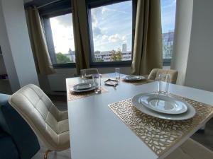 a white table with chairs and a plate on it at UrbanSuites - Modern & Zentral in der City - Dein Zuhause in Stuttgart in Stuttgart