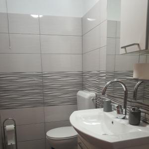 a white bathroom with a toilet and a sink at Apartman Sutivan in Sutivan