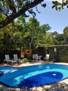 a swimming pool in a yard with chairs and a tree at Chalés e flats Recanto Primavera in Camburi