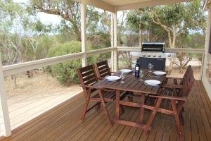 a wooden table and chairs on a porch with a grill at Shiraz Cottage at Allusion in Normanville