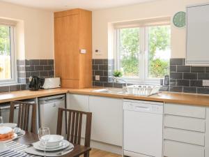 una cocina con armarios blancos y una mesa con sillas. en Sawtons Cottage 2 en Dawlish