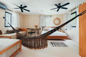 a bedroom with two beds and a hammock at Cucu Hotel El Cuyo in El Cuyo