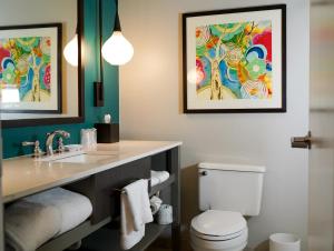 uma casa de banho com um lavatório e um WC com duas fotografias na parede em Hotel Indigo Atlanta Vinings, an IHG Hotel em Atlanta