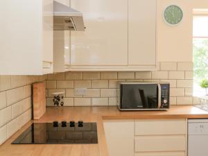 cocina con armarios blancos y microondas en Sawtons Cottage 1 en Dawlish