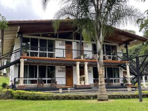 a house with a balcony and a palm tree at Hotel Martino Spa and Resort in Alajuela City