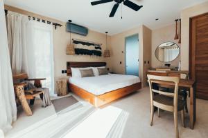 Schlafzimmer mit einem Bett, einem Schreibtisch und einem Spiegel in der Unterkunft Cucu Hotel El Cuyo in El Cuyo