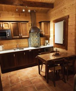 una cocina con armarios de madera, mesa y fregadero en La Dehesilla de Toledo Escapada Romántica Jacuzzi Sillón Tántrico, en Cobisa