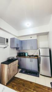 a kitchen with white cabinets and a refrigerator at Staycation in Alabang By Angela in Manila