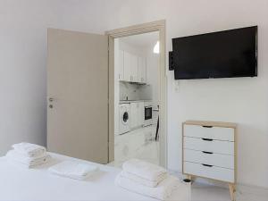 um quarto branco com uma televisão na parede em Hersonissos Modern One Bedroom Apartment Beachside em Hersonissos