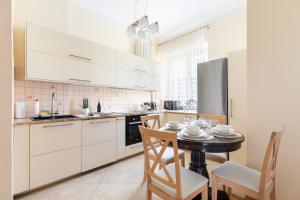 a kitchen with white cabinets and a table with chairs at P&O Serviced Apartments Plac Konstytucji in Warsaw