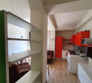 a small kitchen with red cabinets and a living room at Bakuriani K-2 Apartment in Bakuriani +6 photos
