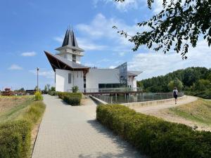 ein Gebäude mit einem Kirchturm und einer Person, die einen Bürgersteig hinuntergeht in der Unterkunft Favorite Vendégház in Poroszló