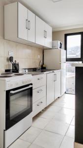 a white kitchen with white appliances and a window at Amanecer del Fuego II in Ushuaia