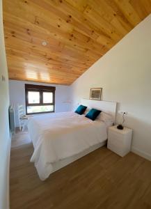 a bedroom with a large white bed with a wooden ceiling at Casa Los Rinocerontes in Penagos