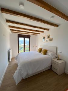 a white bedroom with a large bed and a window at Casa Los Rinocerontes in Penagos