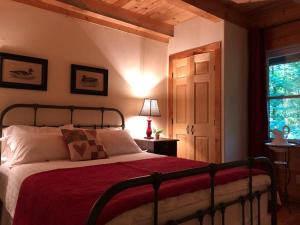 a bedroom with a bed with a red blanket and a window at Quiet, cozy and comfortable chalet in Val-des-Lacs