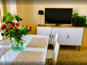 a living room with a table with a television and flowers at Scandinavian Desing Home 37 City Center in Kamppi in Helsinki