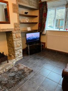 a living room with a television and a fireplace at Cosy cottage with a canal view in Hebden Bridge