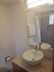 a white bathroom with a sink and a mirror at Hotel Presidente in Ensenada