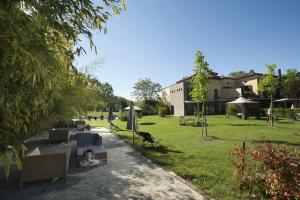 a garden with chairs and umbrellas and a building at Hotel Langhe in Alba