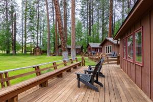 Lake Creek Lodge في Camp Sherman: سطح خشبي مع مقاعد على جانب المنزل