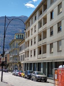 una strada con auto parcheggiate di fronte a un edificio di Casa Battisti a Sondrio