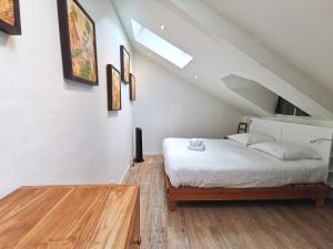 a bedroom with a white bed and a wooden floor at L'Ecrin des bords de l'Erdre - Les Maisons de Madeleine in Nantes