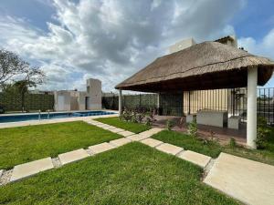 einen Pavillon mit Strohdach neben einem Pool in der Unterkunft Kibira by Andiani Travel in Playa del Carmen