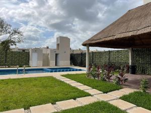 einen Hinterhof mit einem Pool und einem Strohschirm in der Unterkunft Kibira by Andiani Travel in Playa del Carmen