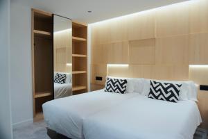 1 dormitorio con 1 cama blanca grande y espejo en Loft Mardevela, en Sanxenxo