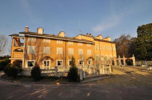 un grand bâtiment orange avec une clôture devant lui dans l'établissement Park Hotel Villa Salzea, à Trofarello