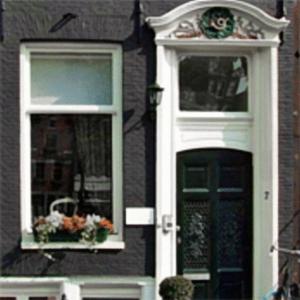 ein Haus mit zwei Fenstern und einer Tür mit Blumen in der Unterkunft The Posthoorn Amsterdam in Amsterdam
