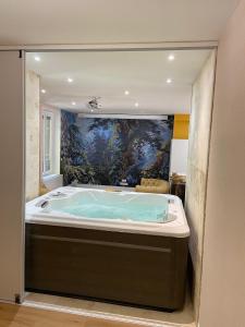 a jacuzzi tub in a bathroom with a painting at Loft "Eden" jaccuzi prestations haut de gamme 92m2-2 chbres in Chamalières