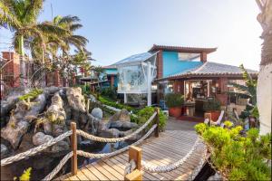 una casa con un puente de madera frente a un edificio en Costa do Sol Boutique Hotel, en Búzios