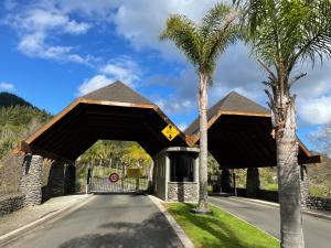 a building with a gate and a palm tree at Pauanui Lakes - Golf Resort in Pauanui