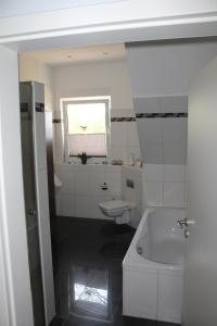a white bathroom with a tub and a sink at Ferienwohnung Grove in Bippen